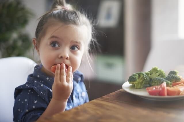 Une petite fille qui mange des légumes